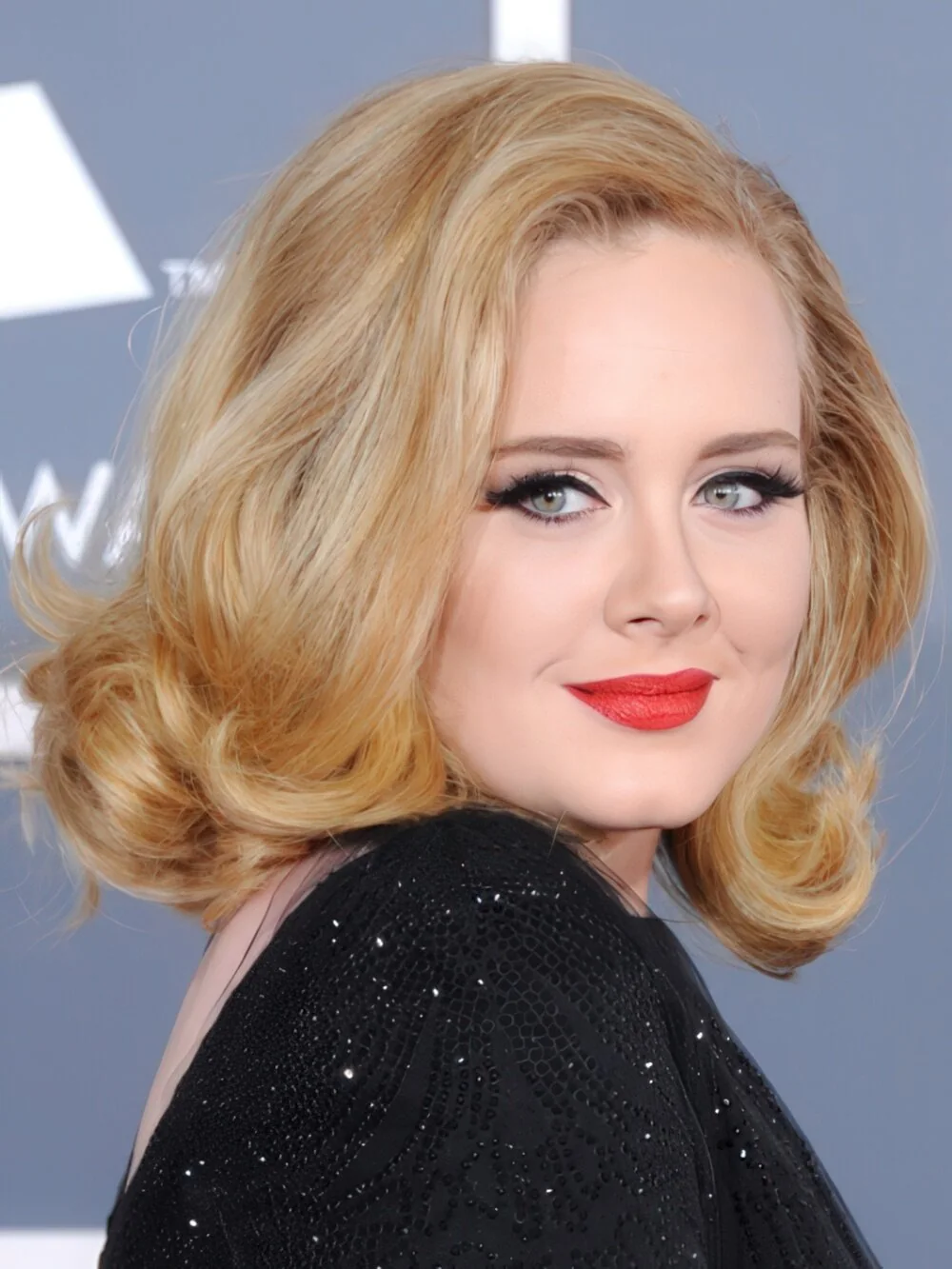 Voluminous blonde shoulder-length curls with a side part.