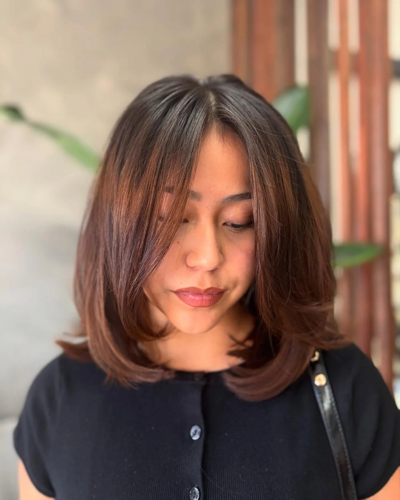 Center-part brunette curtain bangs on a shoulder length lob for a round face