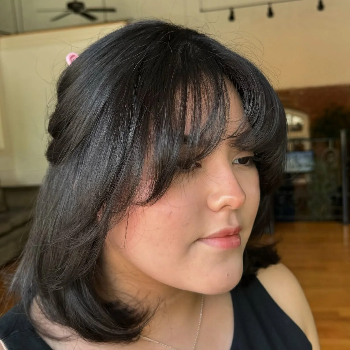 Full curtain bangs with medium black layers framing a round face