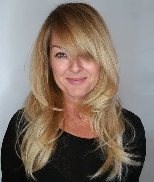 Long layered hair with side-swept bangs framing a round face