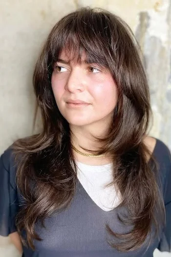 Long shag haircut with wispy bangs and round face framing