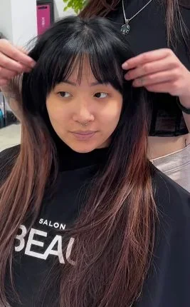 Soft black layers with curtain bangs framing a round face