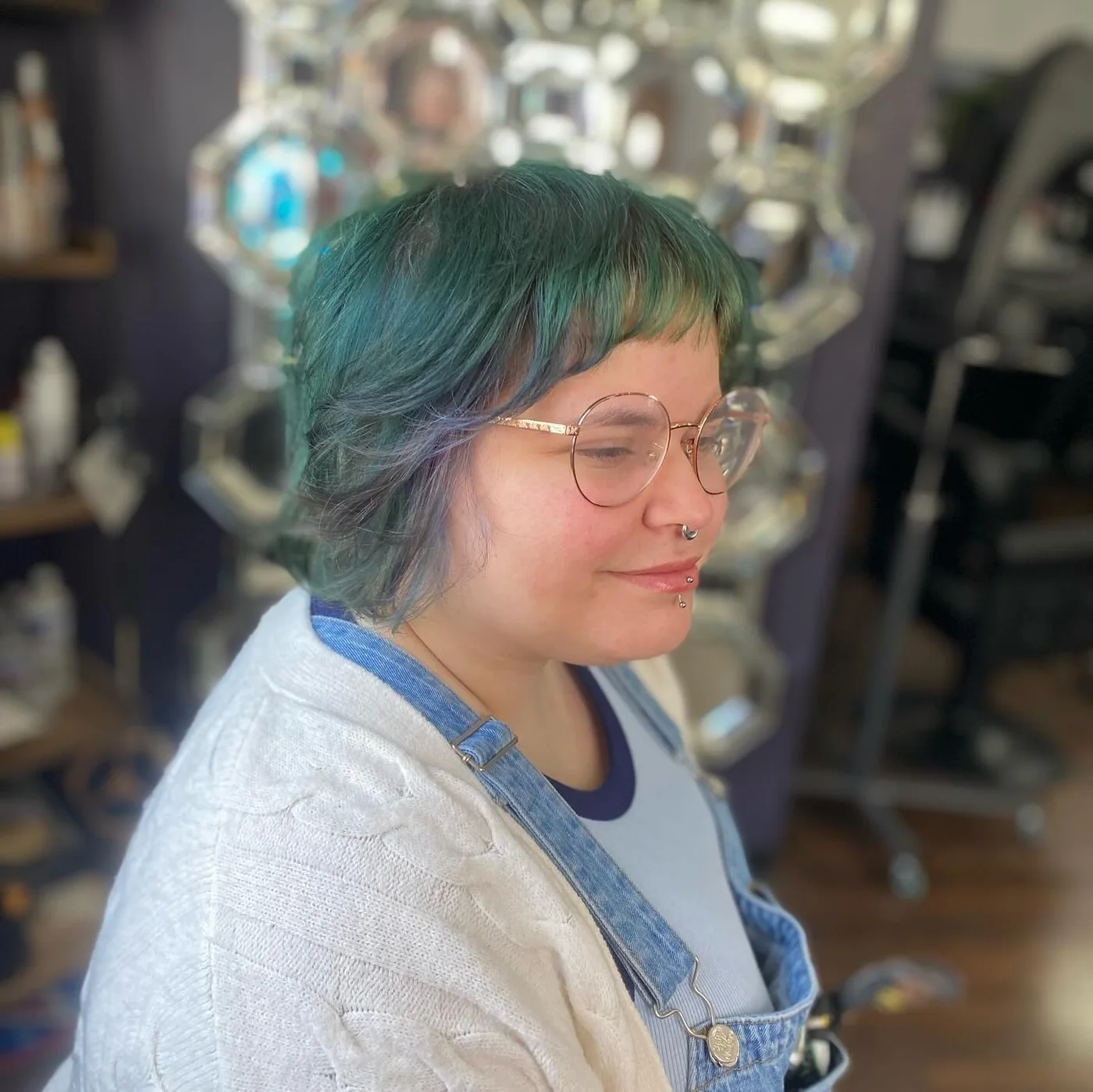 Teal shag haircut with wispy bangs and soft round face framing