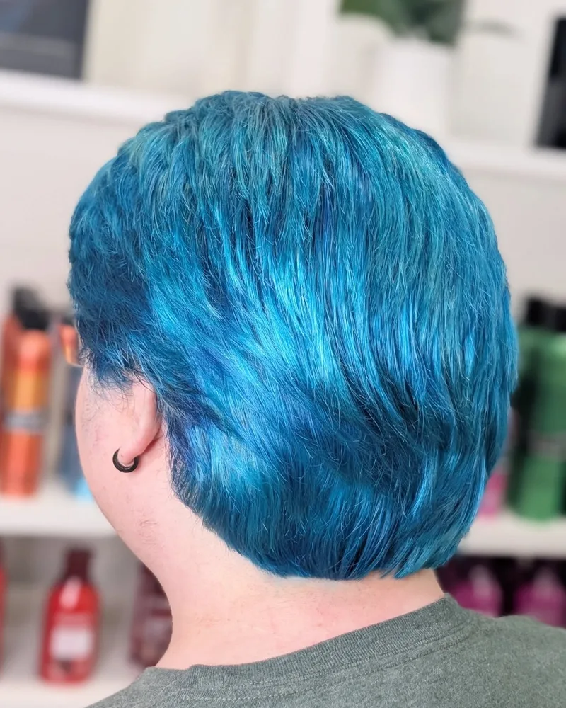 Blue pixie haircut viewed from behind, with a neatly tapered nape, shown as hairstyle inspiration.