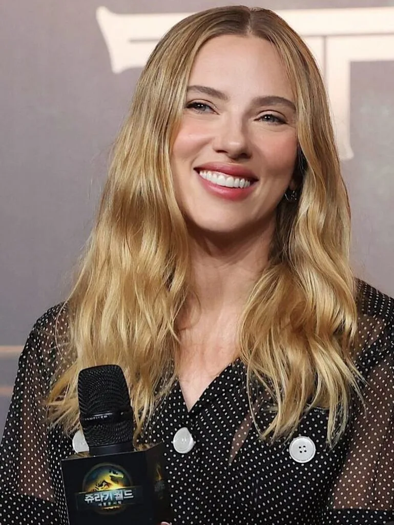 Long blonde waves with a center part, shown as hairstyle inspiration.