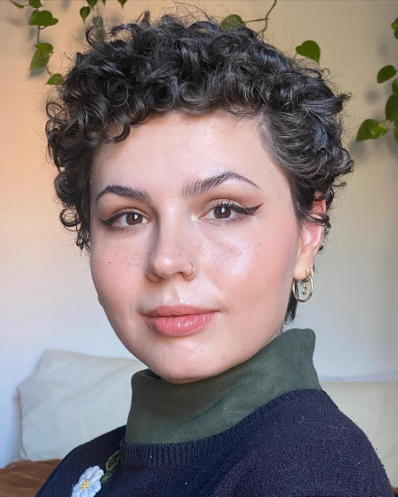 Short dark ringlets above a closely cropped nape, shown as hairstyle inspiration.