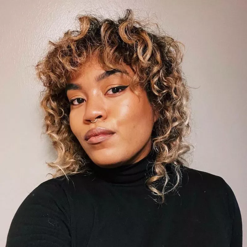 Short curly haircut with brown roots and blonde highlights