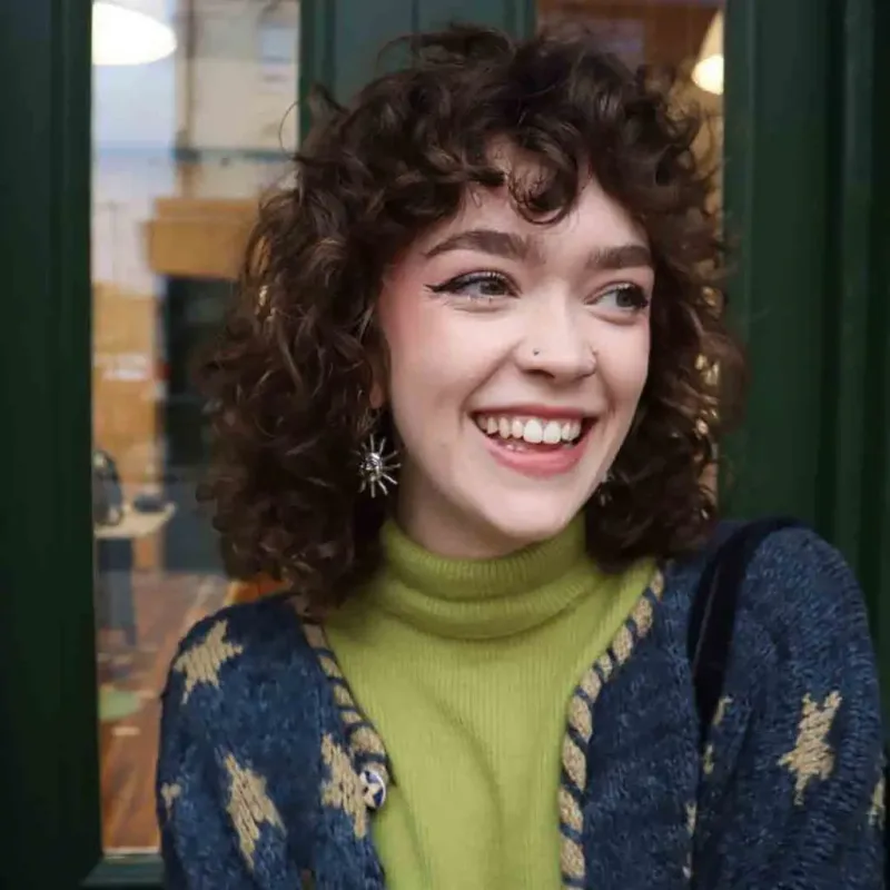 Woman with a chestnut curly shag and curled fringe