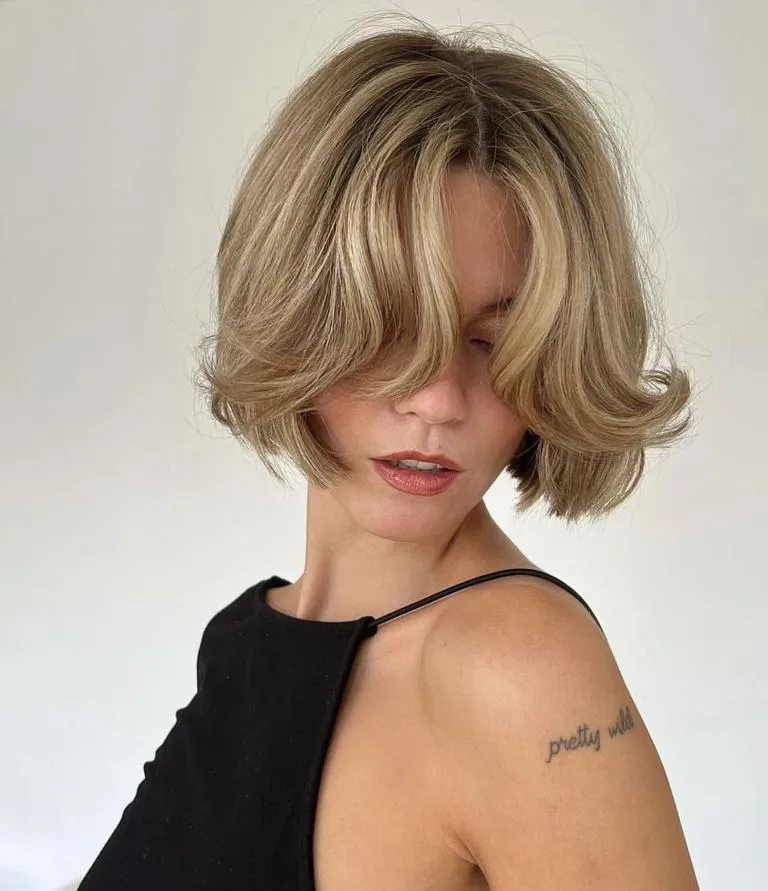 Short blonde bob with parted fringe and curved ends