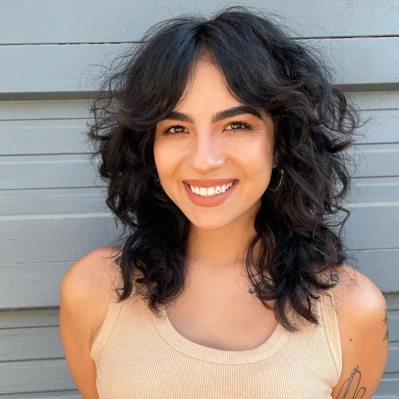Woman with dark shoulder-length waves and a side-swept fringe