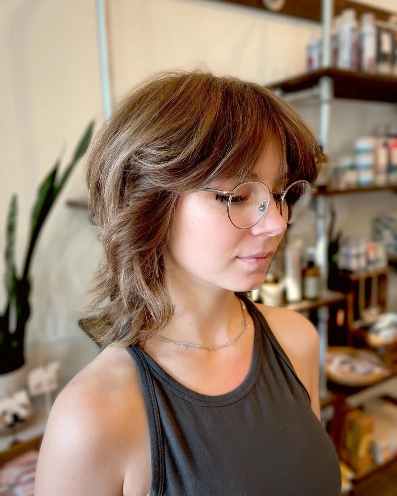 Short layered brunette bob with soft curls and glasses