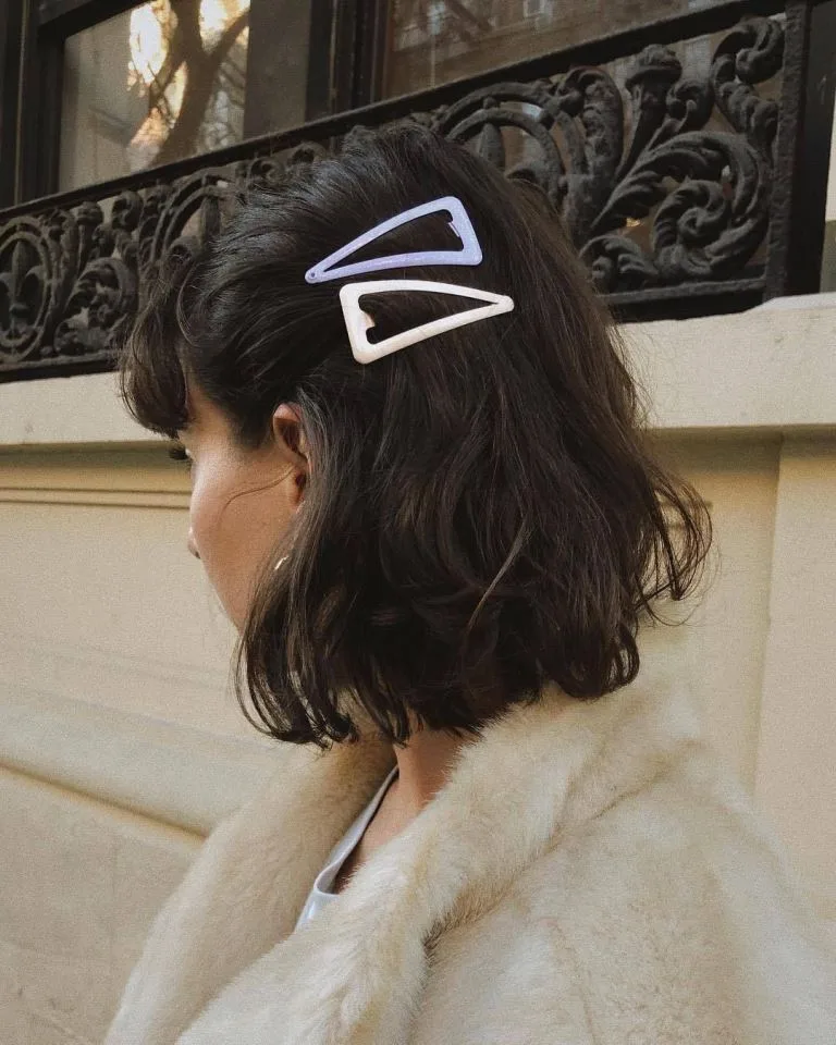 Short dark wavy bob with two triangular clips above the ear