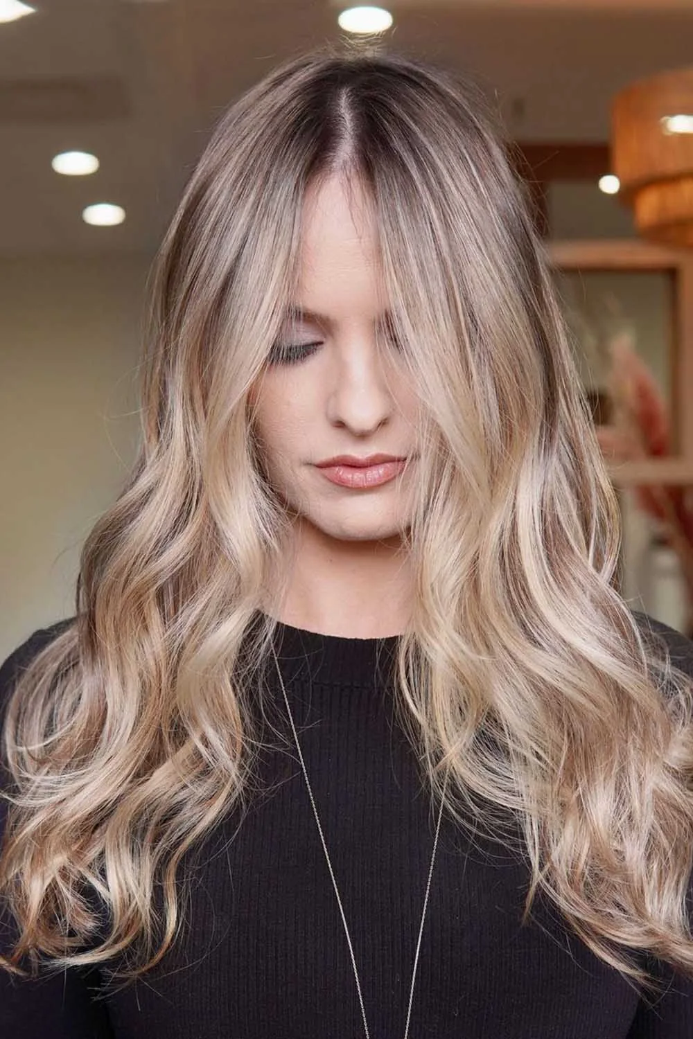 Long creamy blonde waves with darker roots and softly blended sides