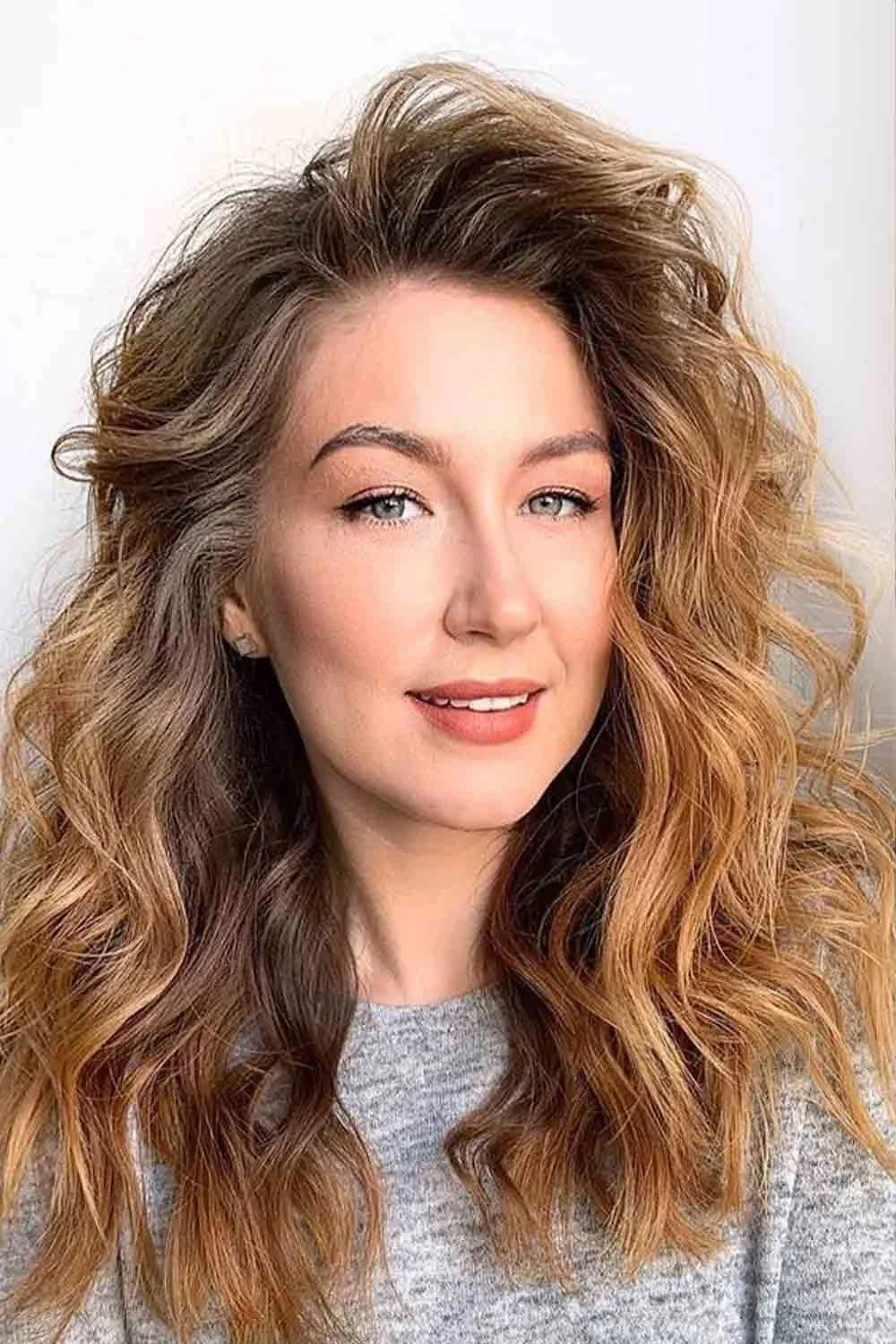 Warm brown-blonde curly hair with lighter golden sections around the face