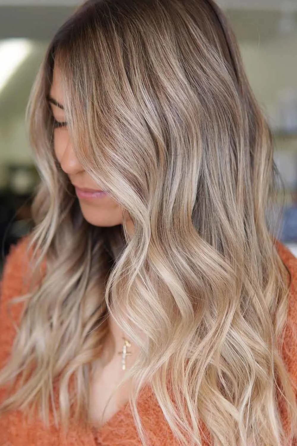 Long beige blonde waves with a dark root area and bright face-side pieces