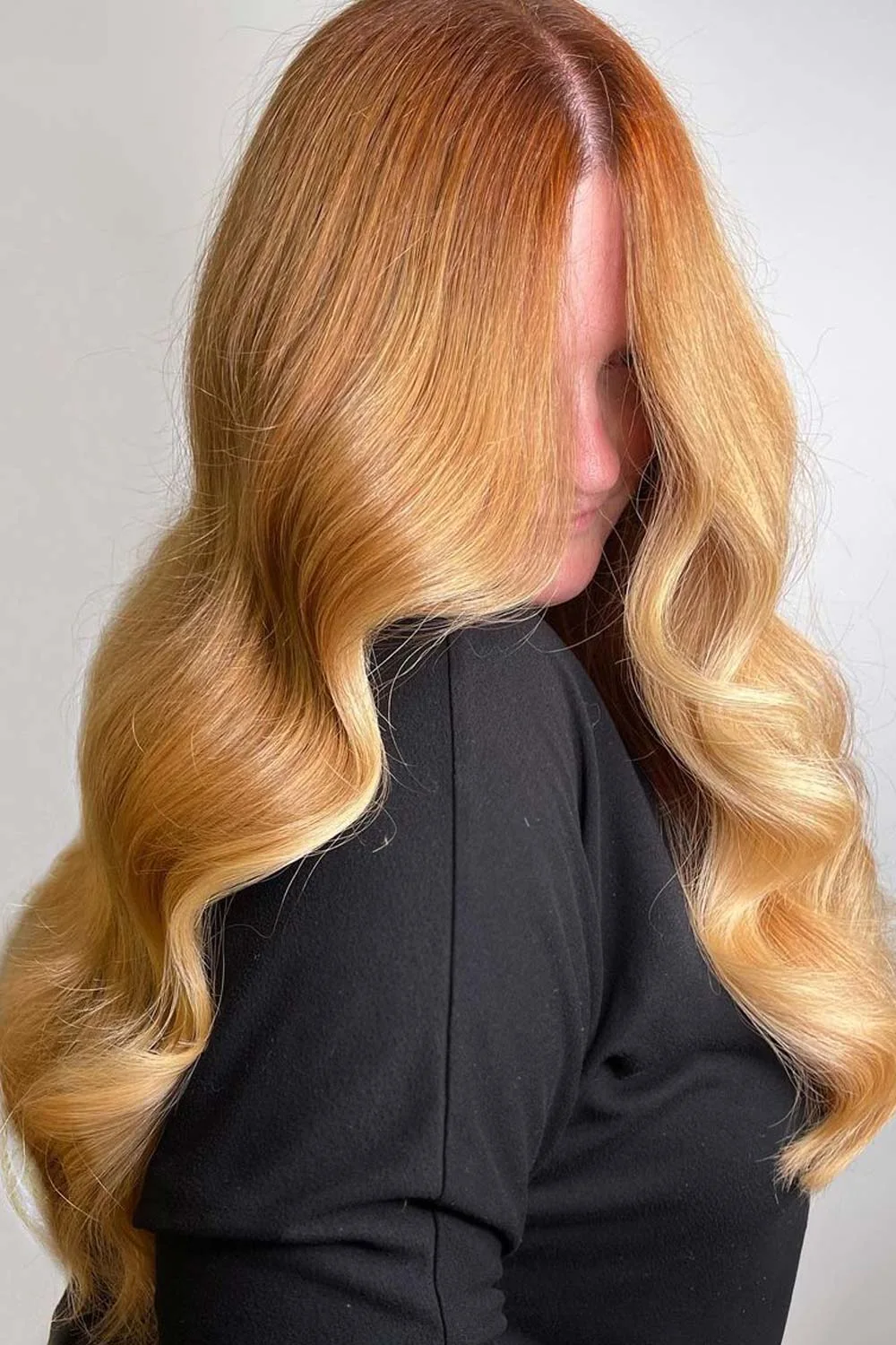 Warm copper-gold blonde hair with broad defined curls through the ends