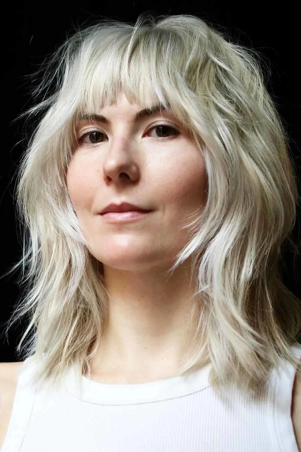 Cool blonde shaggy shoulder-length hair with a short uneven fringe