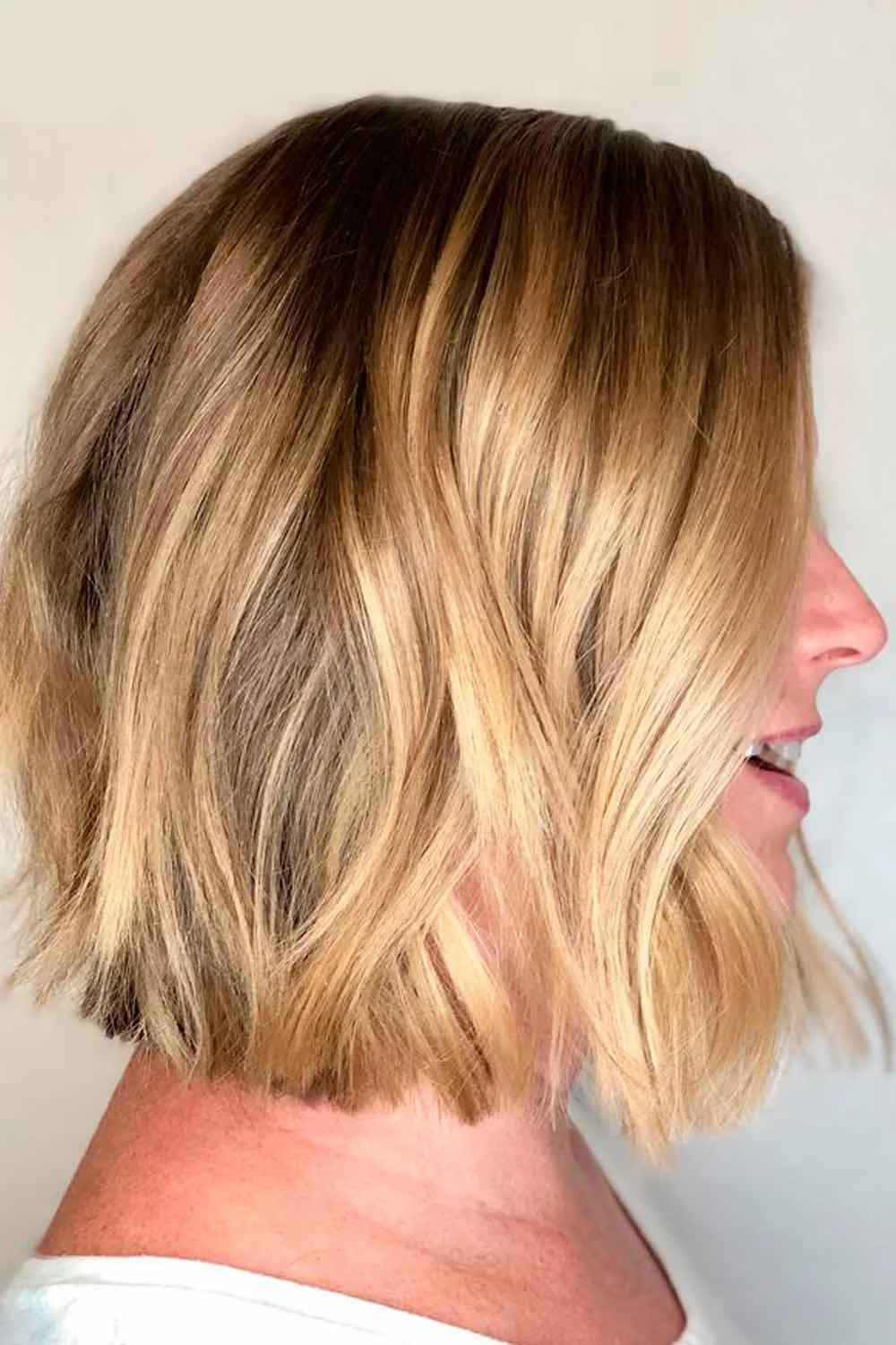 Side view of a champagne blonde bob with loose waves and darker roots