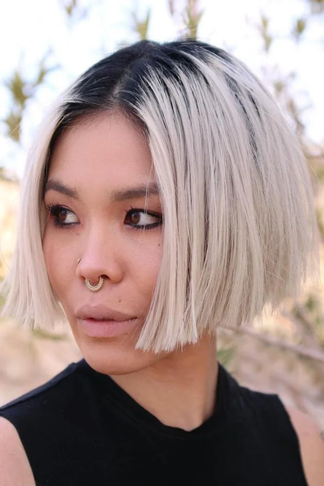 Front view of a blunt pale blonde bob with a dark center root area