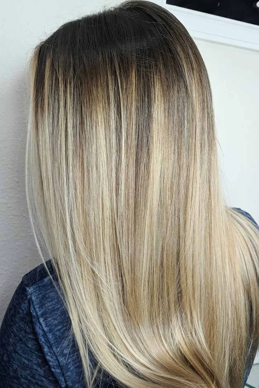 Back view of long straight hair changing from deep brown roots to blonde ends