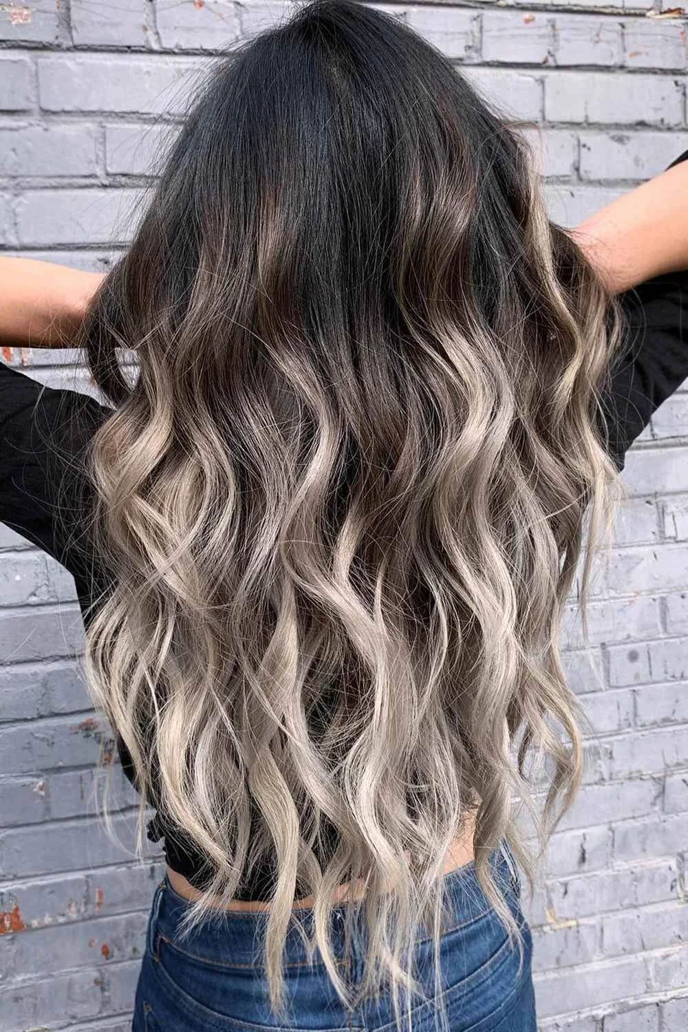 Back view of long hair with deep dark roots and pale blonde curled ends
