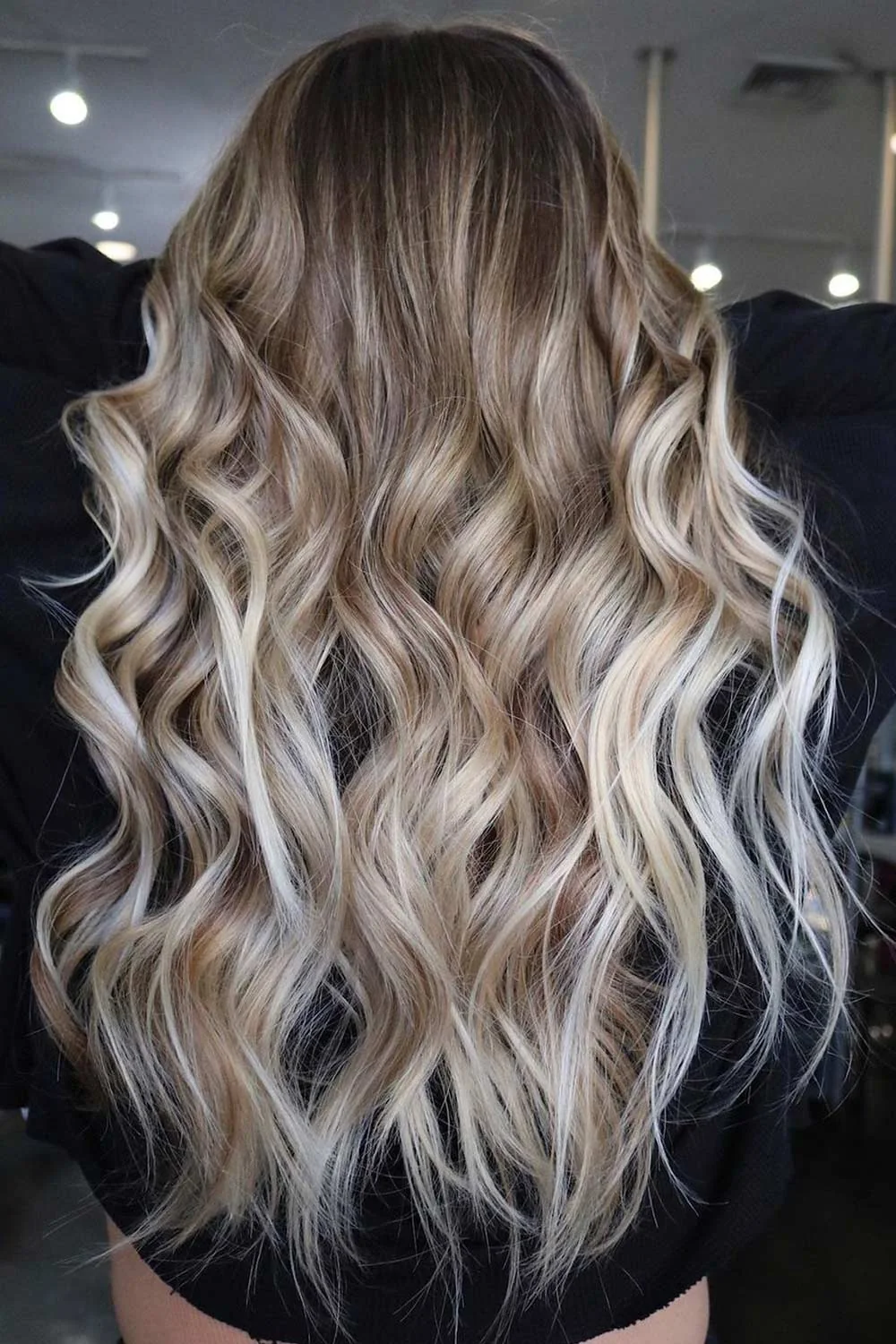 Back view of long brown-rooted hair with pale blonde ribbons through loose waves