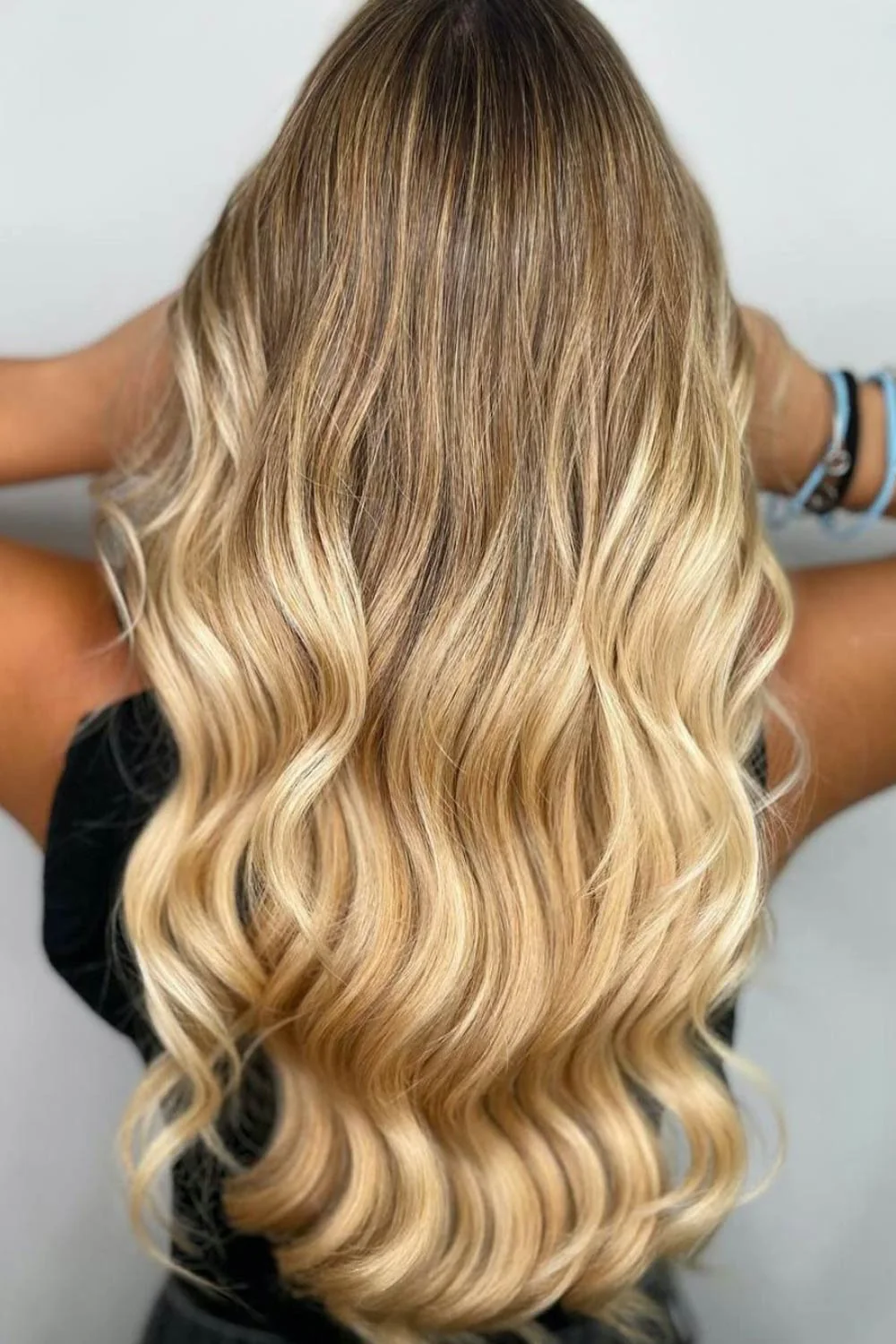 Back view of long broad golden blonde waves with darker roots