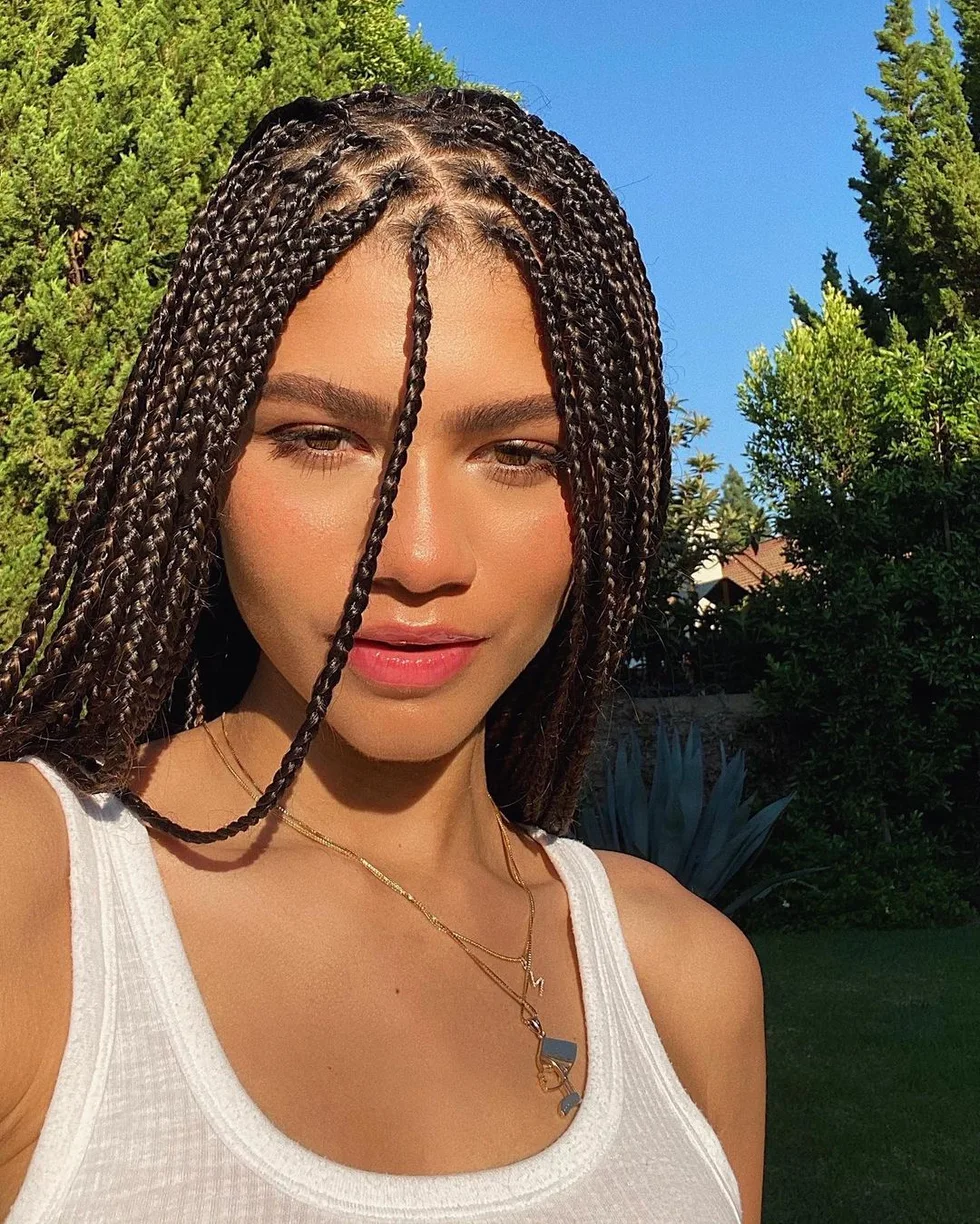 Front view of brunette box braids with a center part and face framing pieces