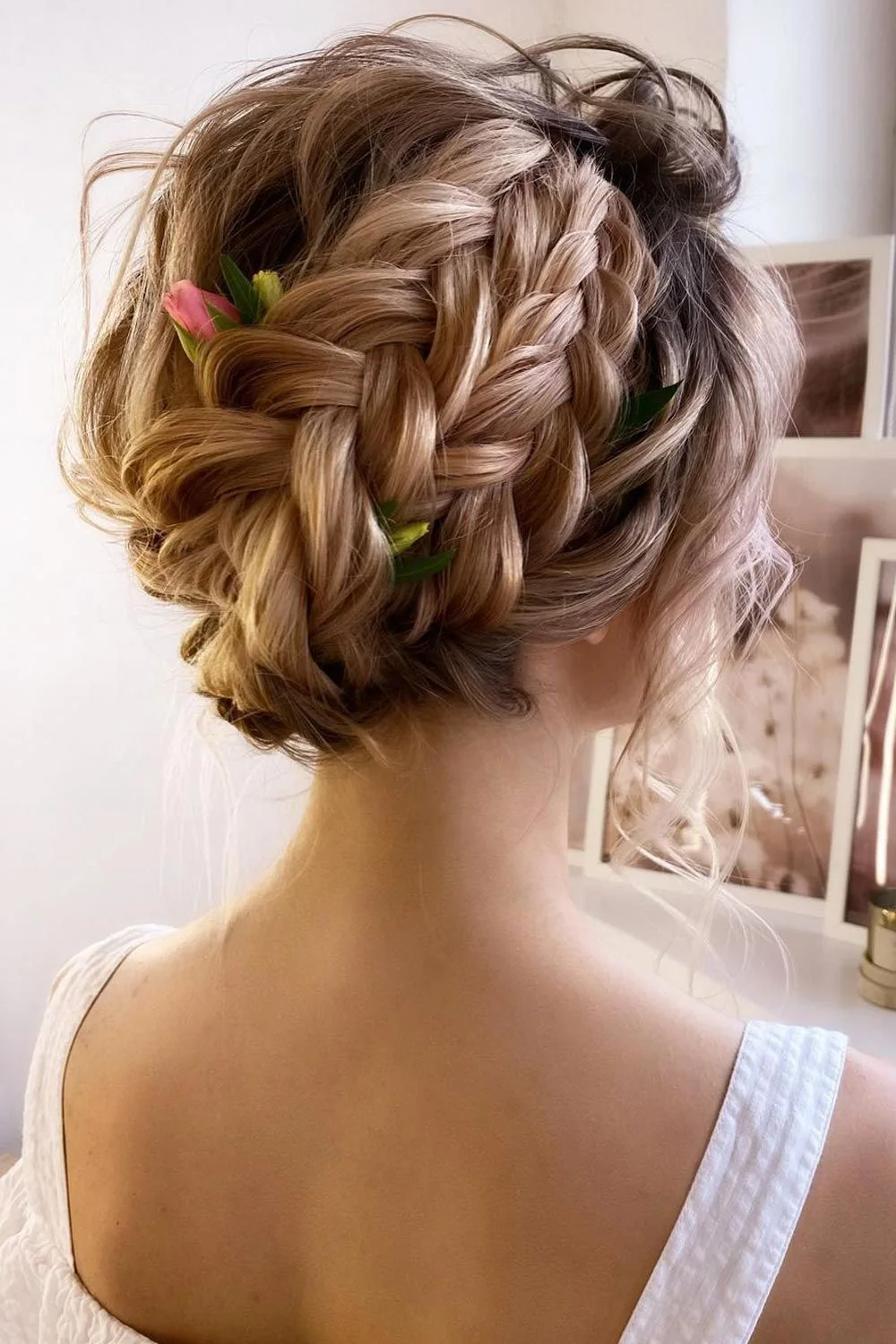 Back-side view of a broad brown braided crown with small pink flowers and green leaves