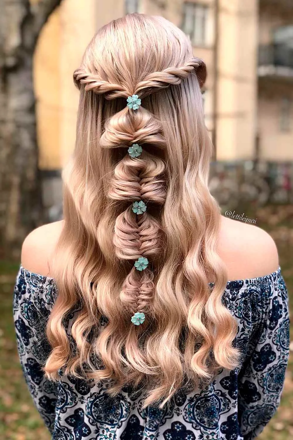 Back view of long pale hair with a looped half-up braid and spaced teal flowers