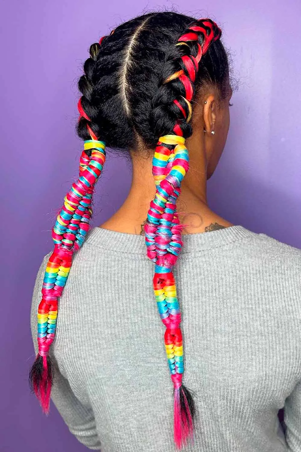 Back-side view of dark twin braids with red ribbon and multicolored wrapped tails