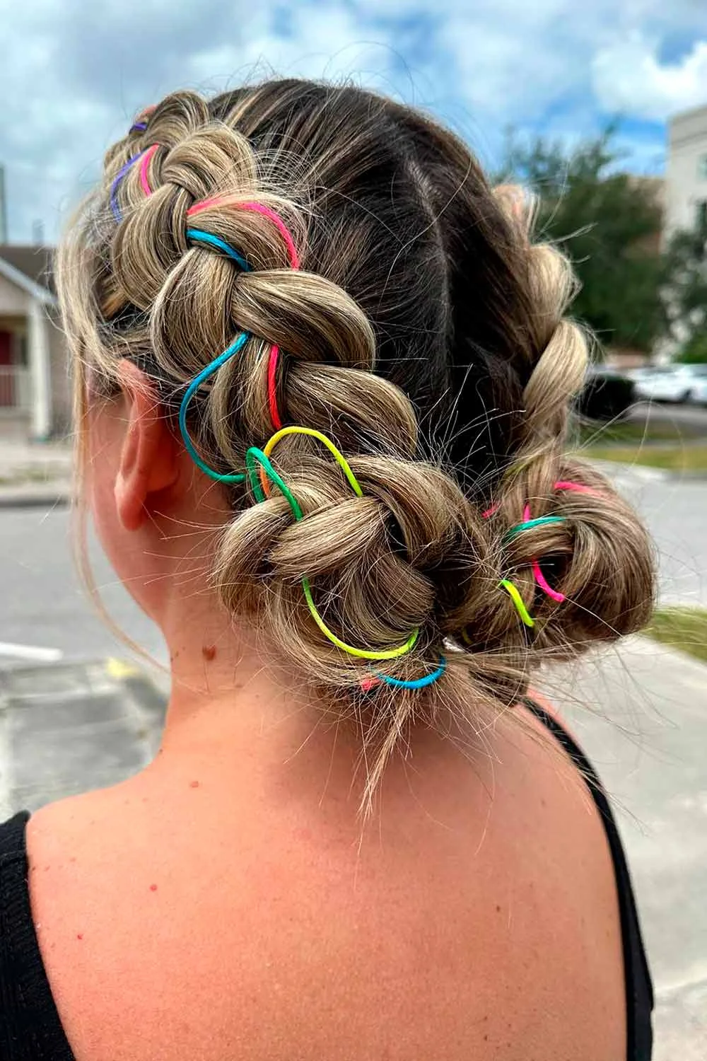 Back view of two broad braids ending in low buns with scattered colored loops