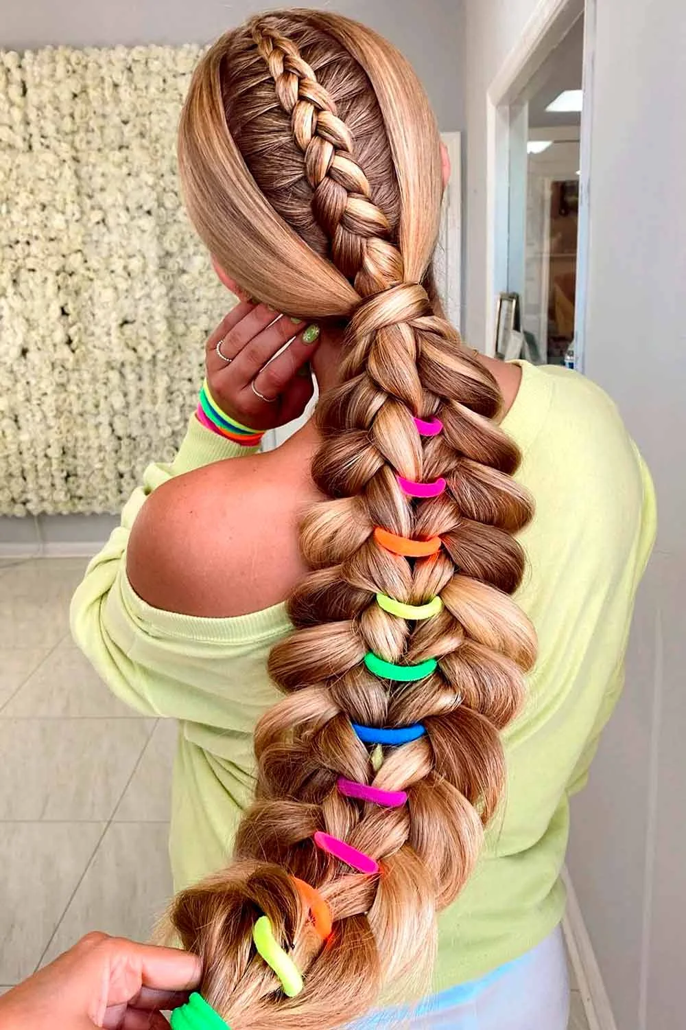 Back view of a broad looped ponytail braid with bright bands spaced down its length