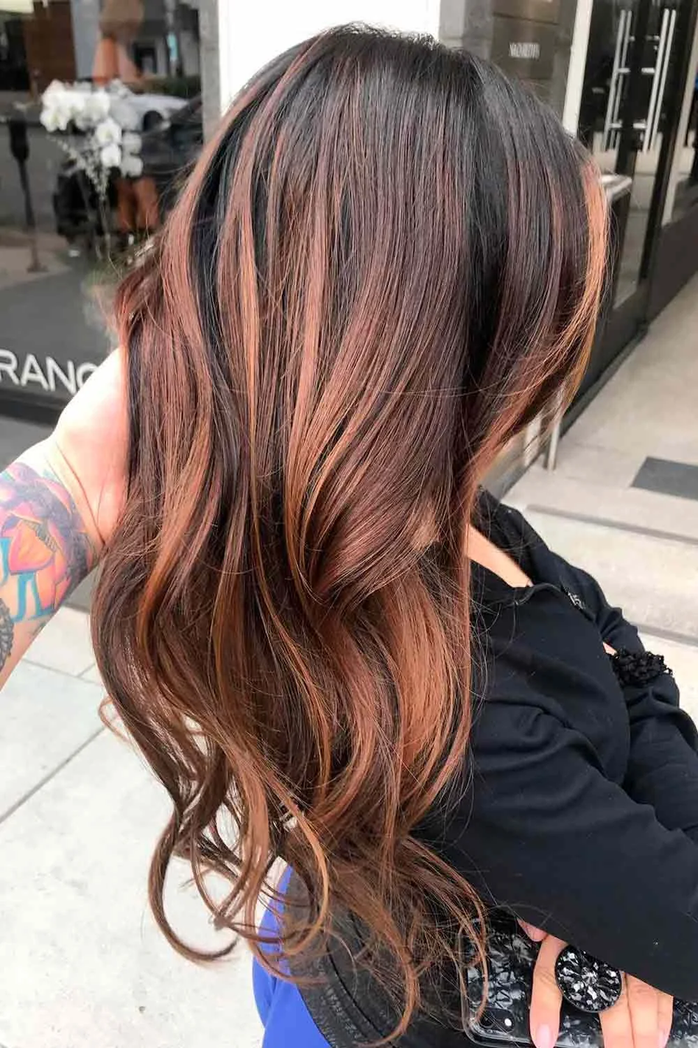 Back-side view of long brown hair with thin copper-warm strands and curled ends