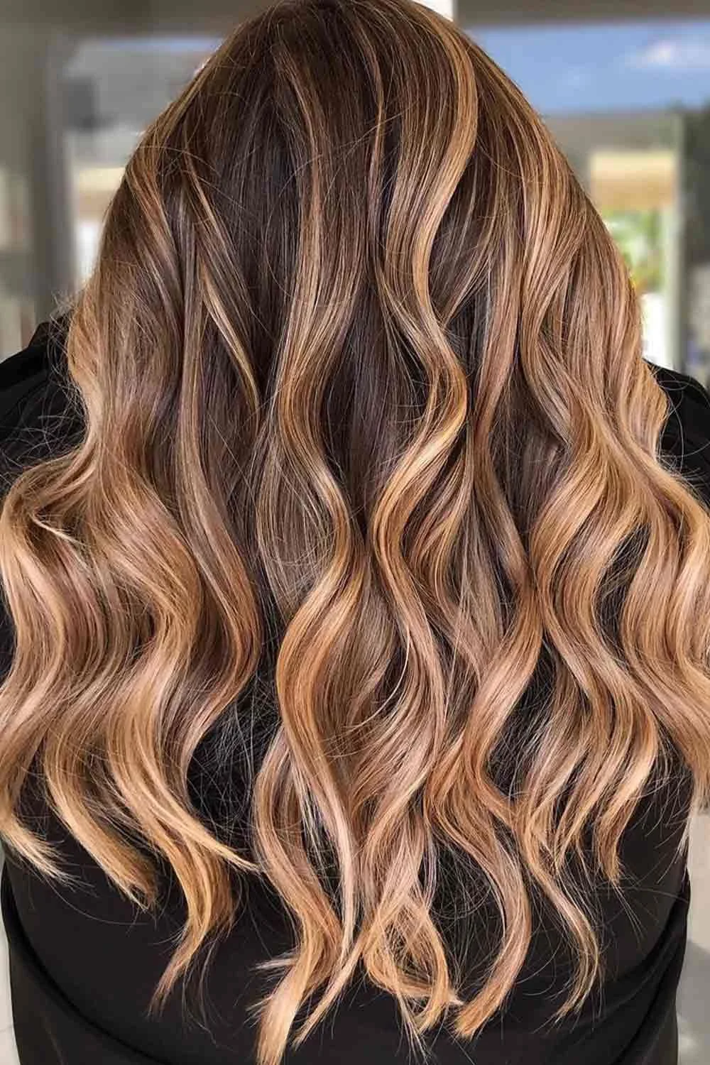 Back view of long brunette waves with golden highlight ribbons