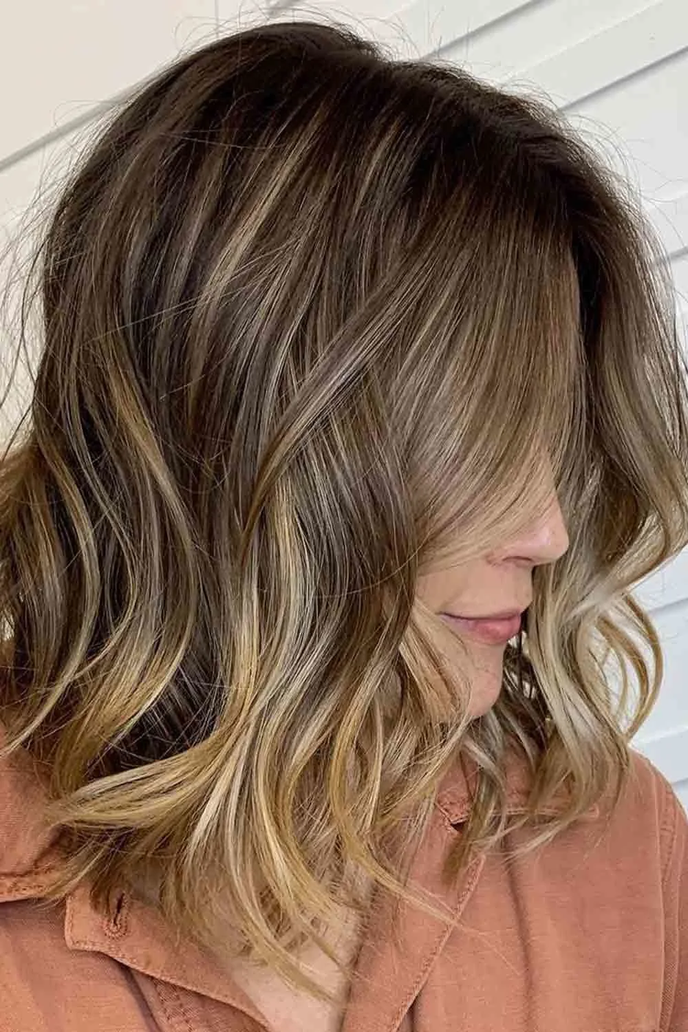 Side view of a wavy brown bob with warm lighter ends