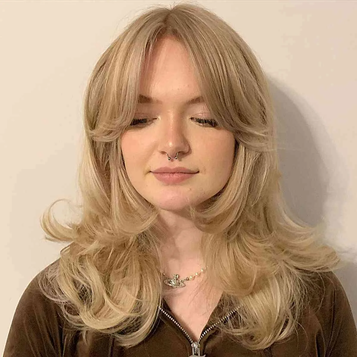 Blonde butterfly haircut with center parted bangs and bouncy long layers