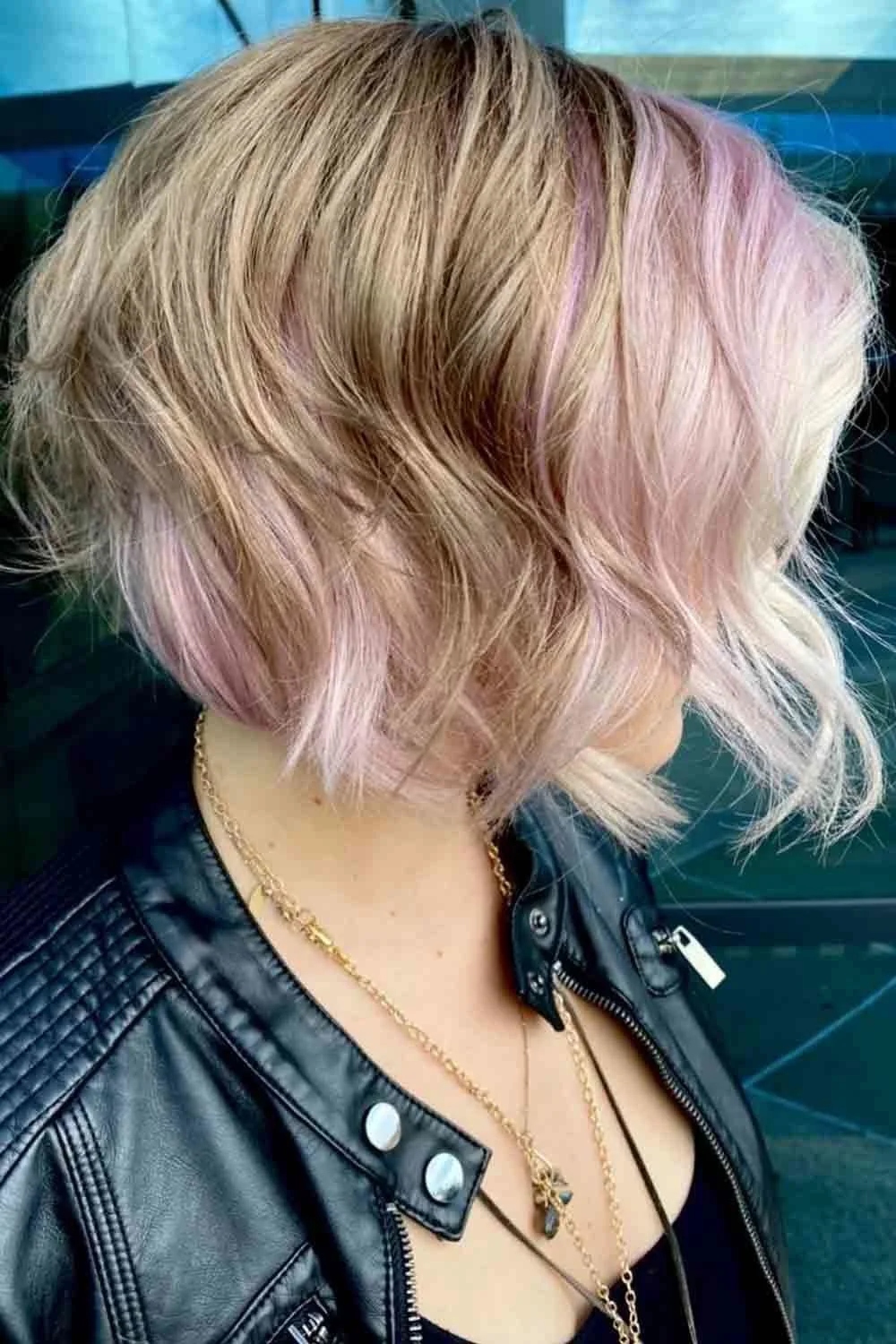 Side-back view of a short blonde bob with soft blush-pink panels around the front and underside