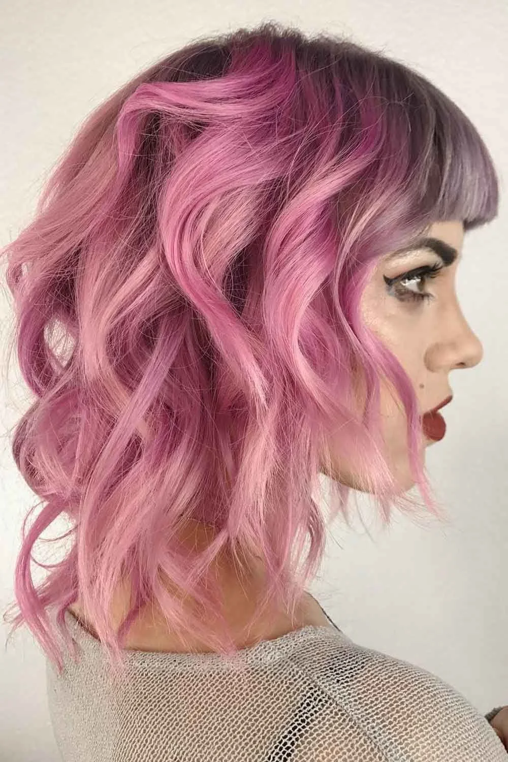 Side portrait of a wavy antique-rose short bob with short straight bangs and darker crown
