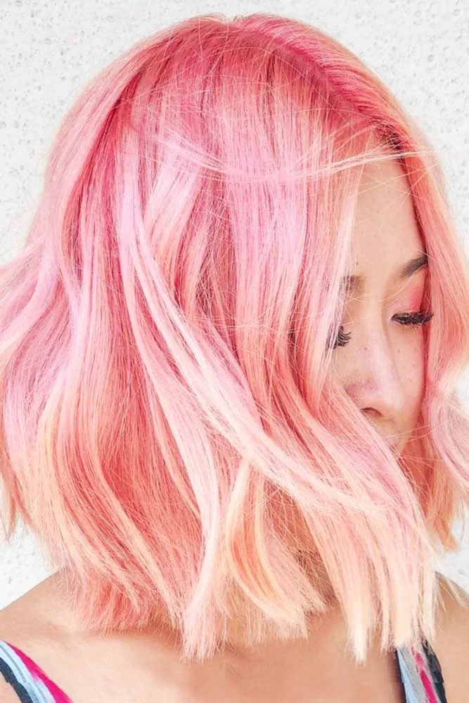 Side view of a short pink bob with pale peach ends, loose bends and airy front pieces