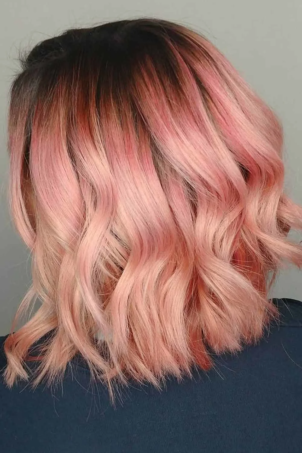 Back view of a wavy bob with brown roots and peach-pink lengths