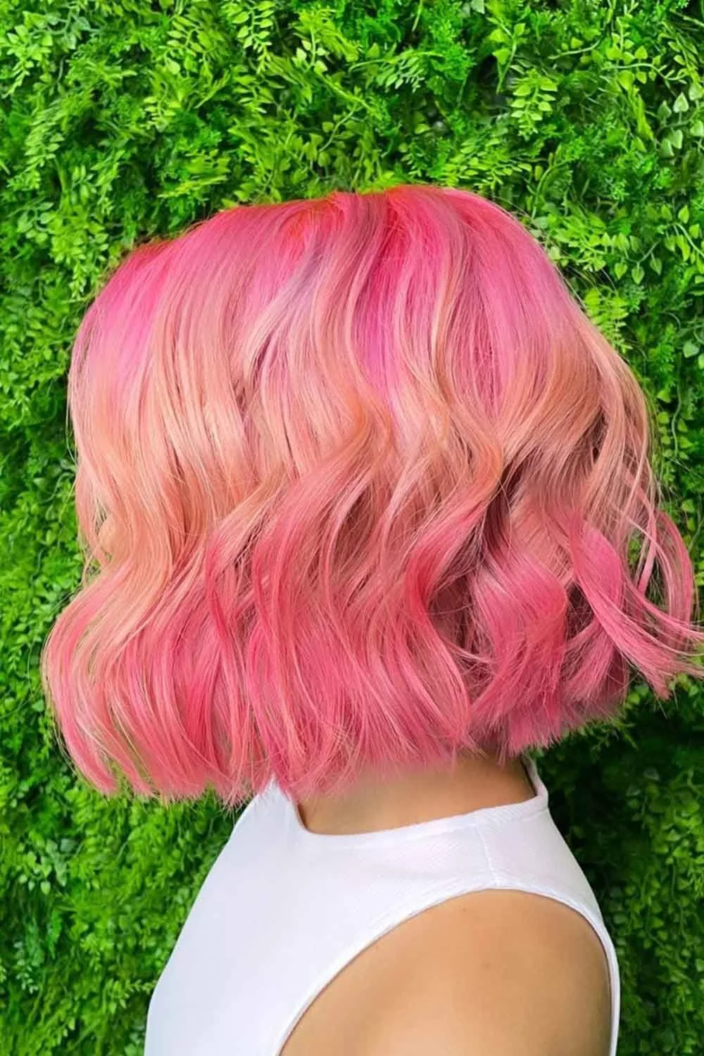Back-side view of a short wavy bob with bright pink roots and peach-orange curved ends