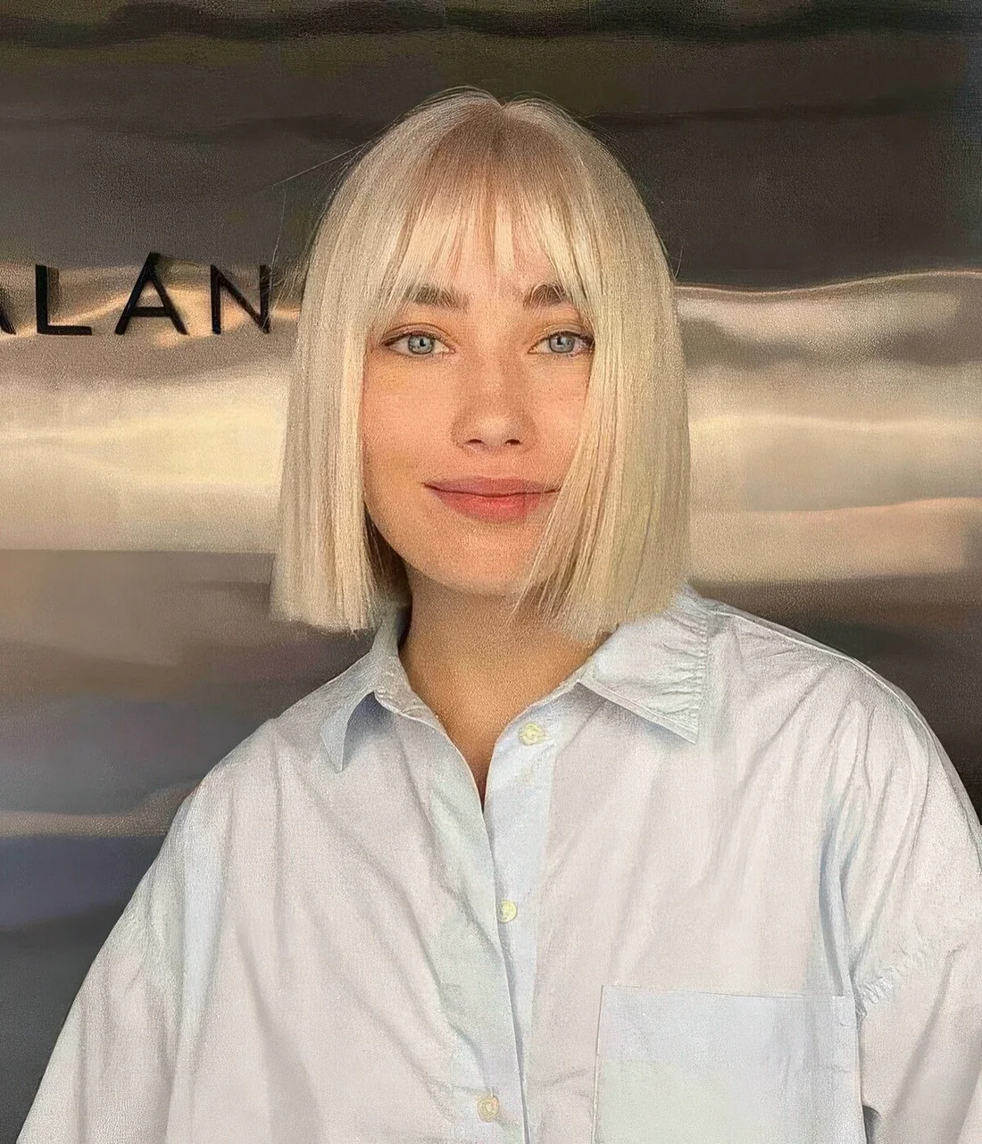Blonde straightened bob with wispy bangs.