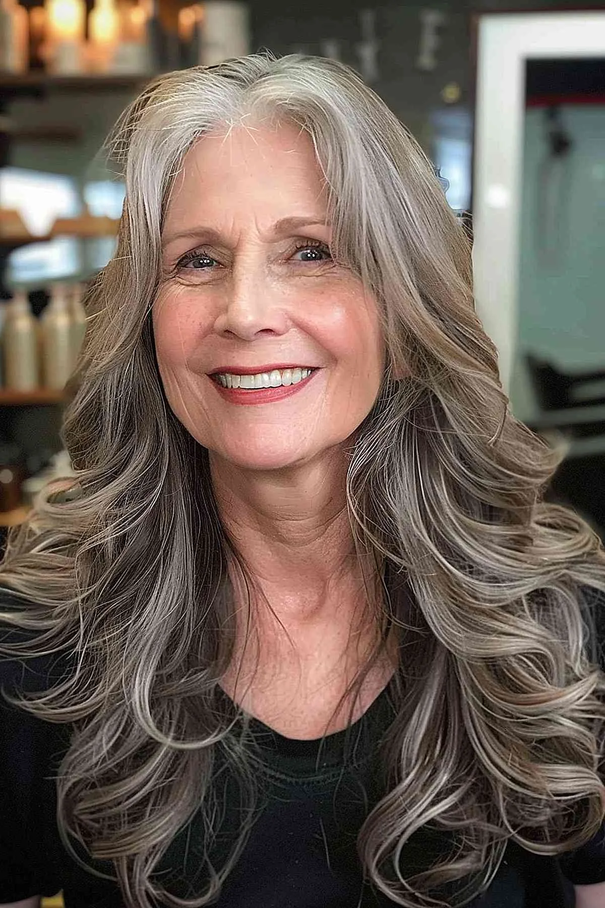 Older woman with long smoky gray layers and soft face-framing waves
