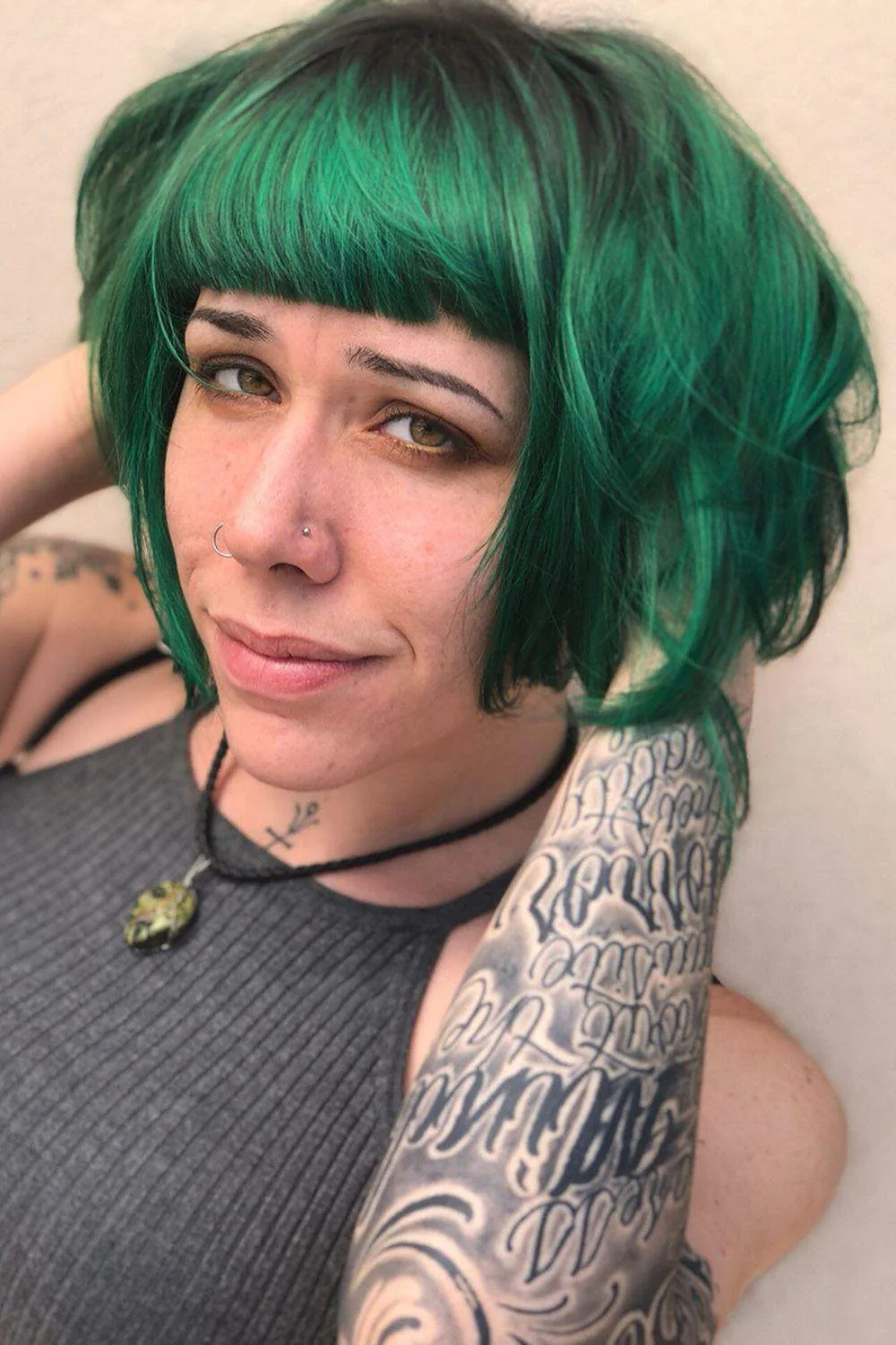 Emerald green bob with a short straight fringe and darker root detail
