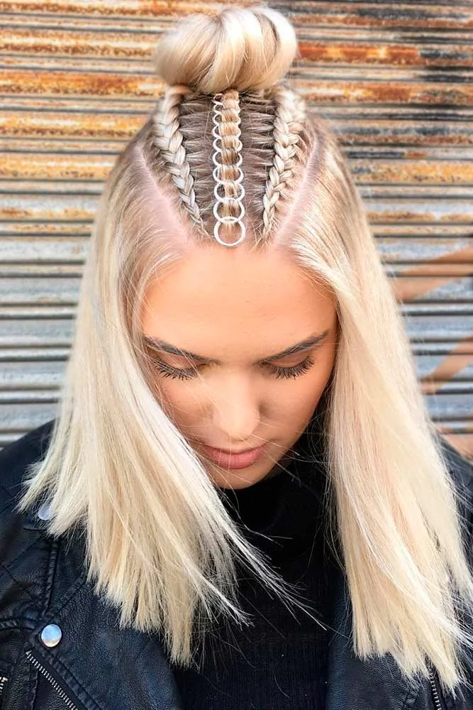 Front-top view of a blonde half-up bun with three scalp braids and a line of silver rings