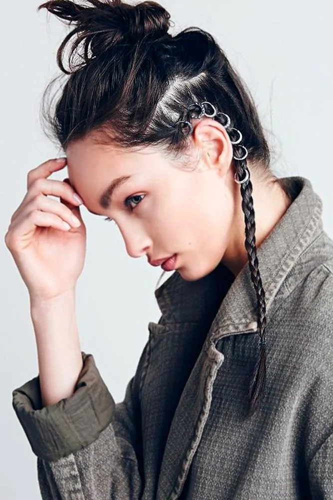 Side portrait of dark hair in a high messy bun with one narrow ringed braid beside the ear