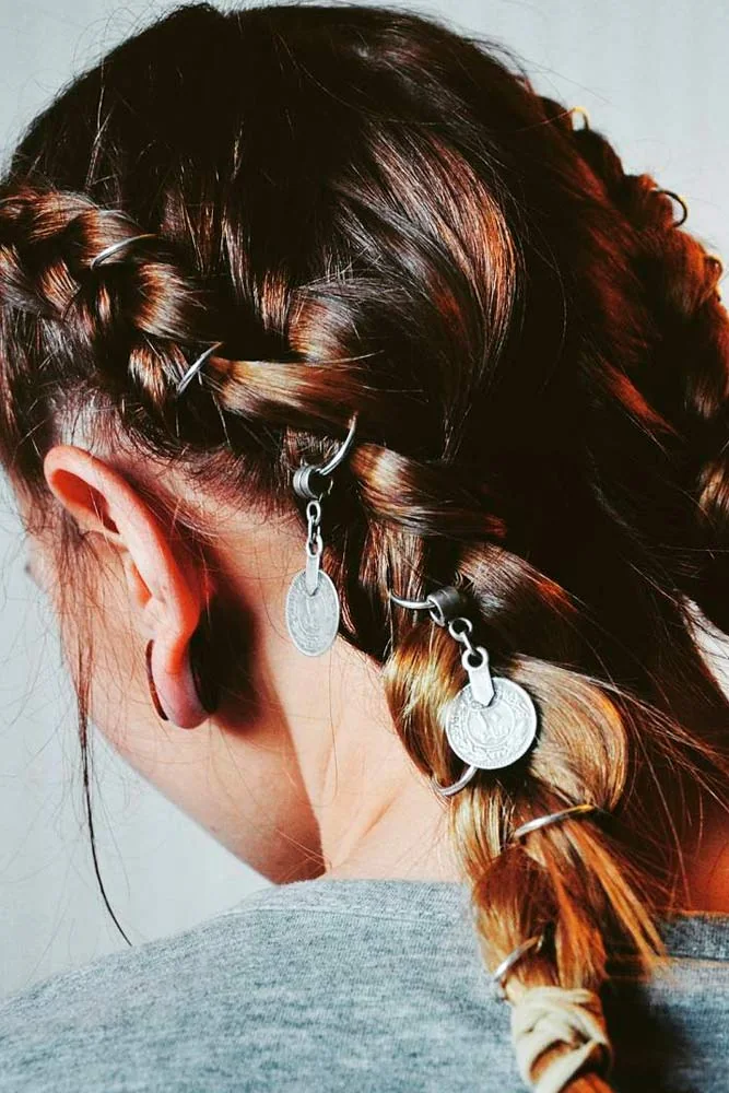 Back-side view of a braid gathered low with silver disc charms hanging near the ear and nape