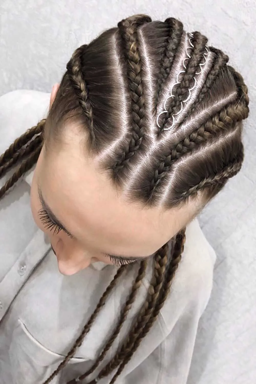 Top view of several dark scalp braids with silver rings along one diagonal section