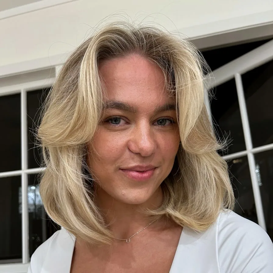 Soft blonde curtain bangs with shoulder length layers for a woman over 40